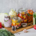 Cooking pickled vegetables. Salting various vegetables in glass jars for long-term storage. Preserves vegetables in glass jars. Variety fermented green vegetables on wood board