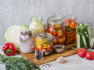 Cooking pickled vegetables. Salting various vegetables in glass jars for long-term storage. Preserves vegetables in glass jars. Variety fermented green vegetables on wood board